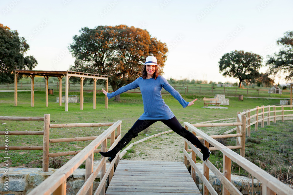 Stylish young woman with whithe hat on a wooden bridge