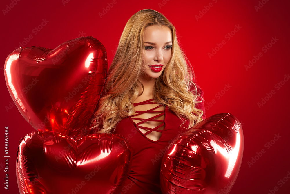 Beautiful smiling  woman posing on red  background and holding b