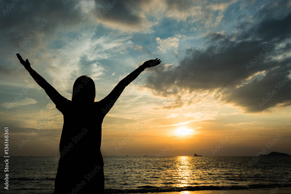 silhouette of woman pointing with finger in sky on the beach