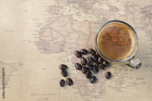 world map on cup of fresh espresso on map background, view from above