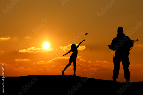 silhouette of a man with a gun and a little girl playing with a paper airplane