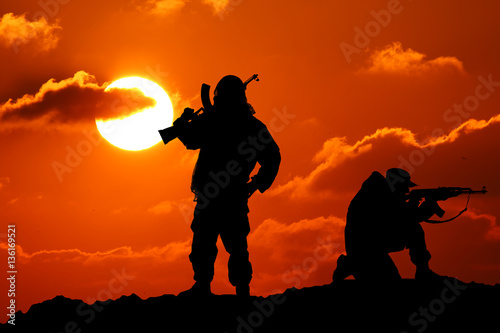 Two men shot dead a soldier holding a gun and Vit mountain piktureskie bakkdrop al sunset © YURII Seleznov
