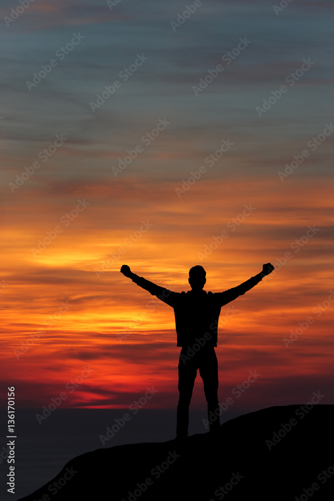 man against the sea standing on a mountain top looking into the distance