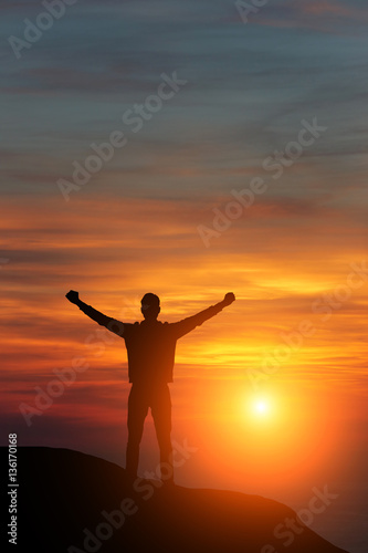 man against the sea standing on a mountain top looking into the distance