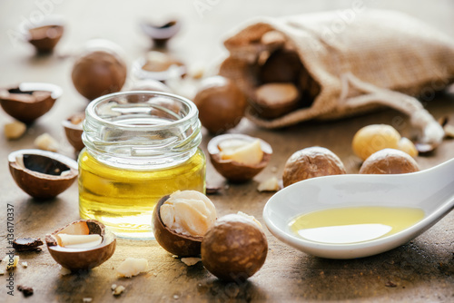 Tableau sur toile Natural macadamia oil and nuts on wooden board. Healthy product