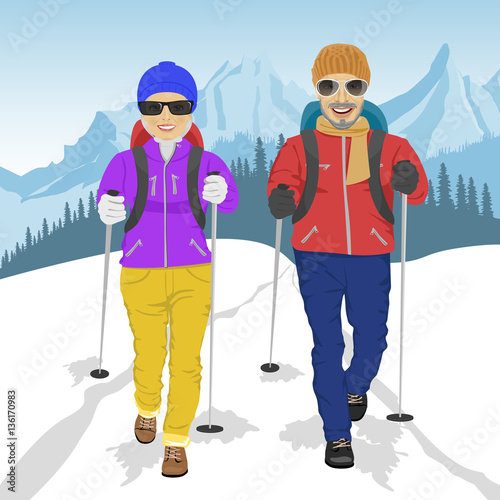 senior couple wearing hiking gear walking in mountains in winter