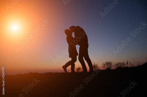 silhouette guy and girl on a beautiful sunset holding hands © YURII Seleznov