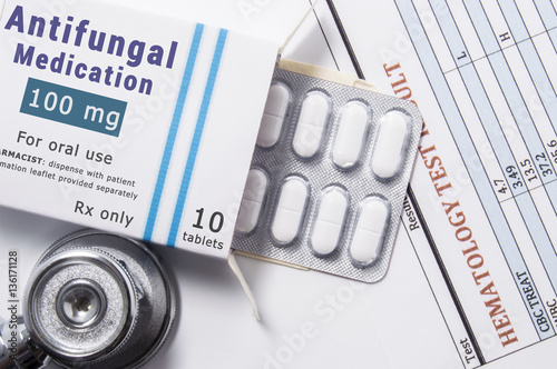 Antifungal drug. Open paper packaging box of medication with name group of drug Antifungal, blister with pills, next to stethoscope and blood test results. Concept for treatment of fungal diseases photo