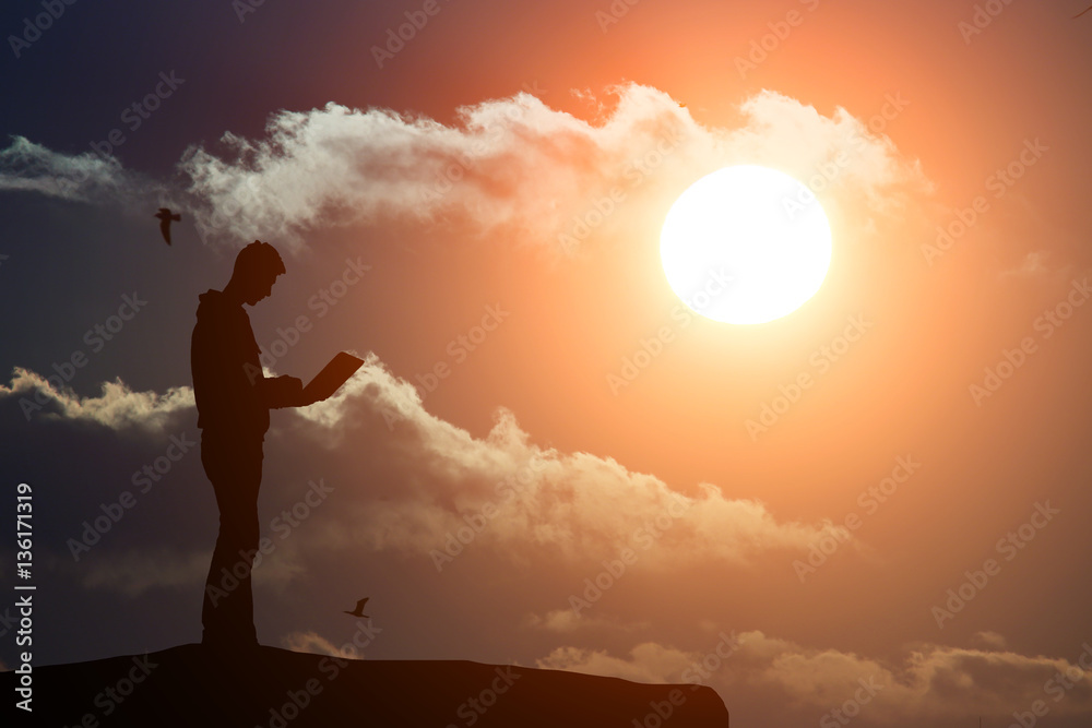 silhouette of a man atop a mountain working on a laptop on the background of beautiful species
