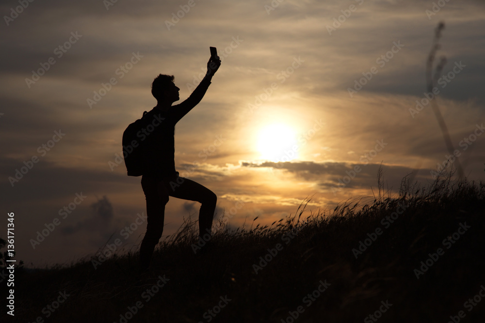 a man standing on a hill looking link on the background of a beautiful sunset
