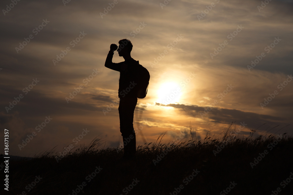 man against the sea standing on a mountain top looking into the distance
