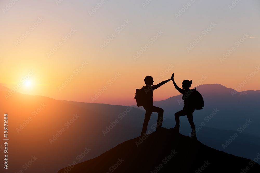 Male and female hikers climbing up mountain cliff and one of them giving helping hand. People helping and, team work concept.