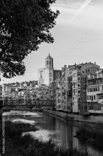 Onyar river crossing the downtown of Girona with bell tower of gothic Cathedral of Saint Mary in background. Gerona, Costa Brava, Catalonia, Spain. Monochrome image: black and white.