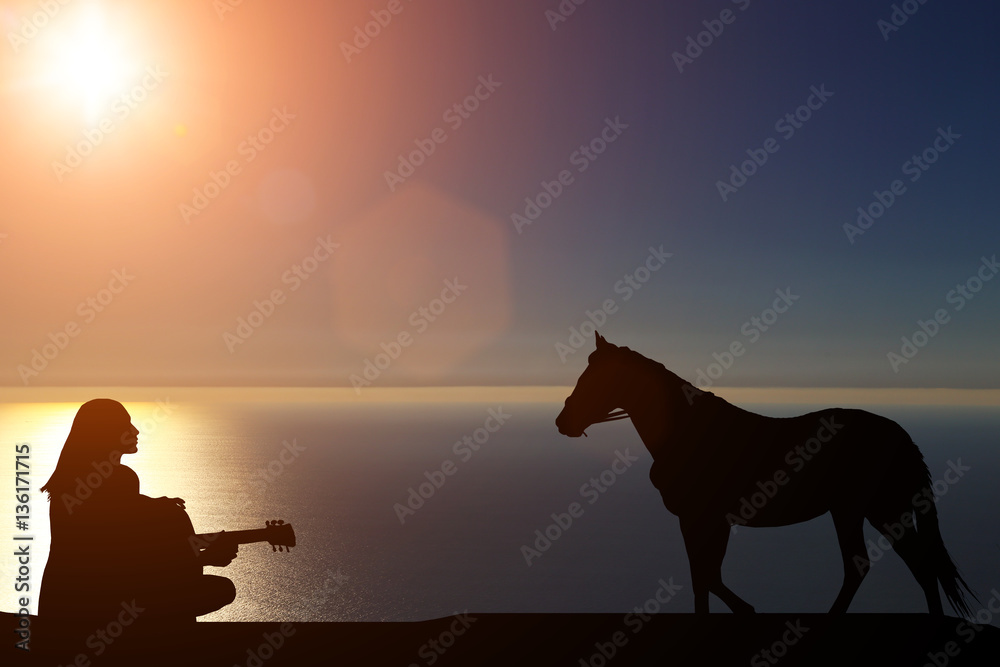 silhouette of a horse walks by the sea and a girl playing a guitar on a background of a beautiful sunset