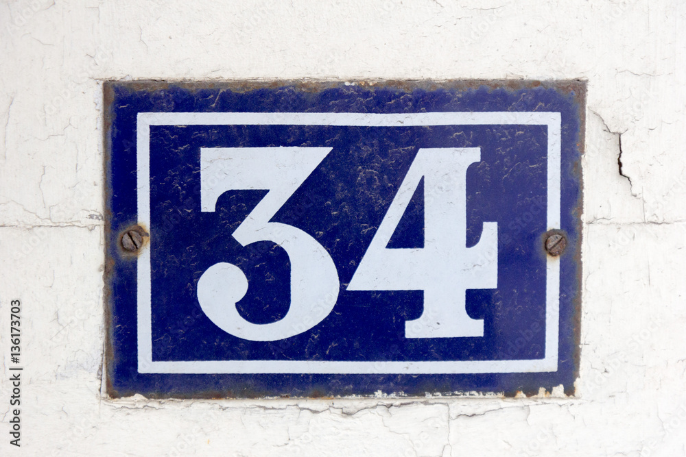 Number 34 (thirty four) in white on a blue metal plate Number 34 (thirty four) in white on a blue metal plate
