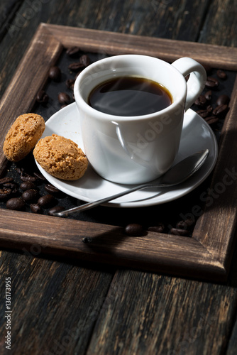 cup of black coffee and cookies on a wooden tray