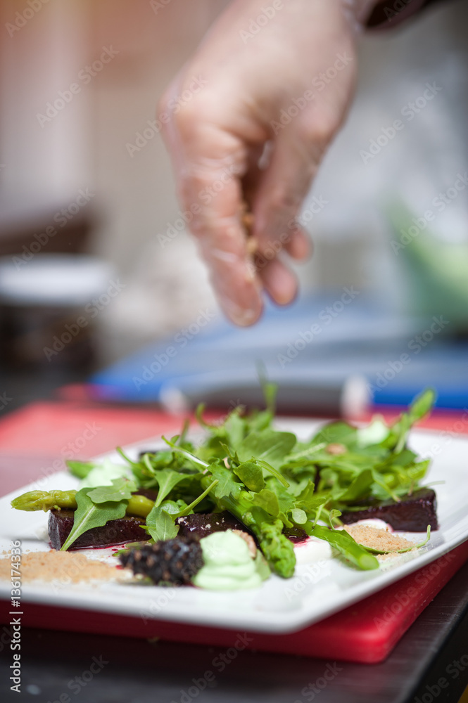 Male chef cooking salad with arugula and beet