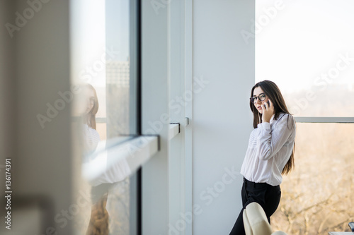 Business woman speak on phone near big office windows in modern smart space. Free Download Business woman speak on phone near big office windows in modern smart space. - GFXLoad
