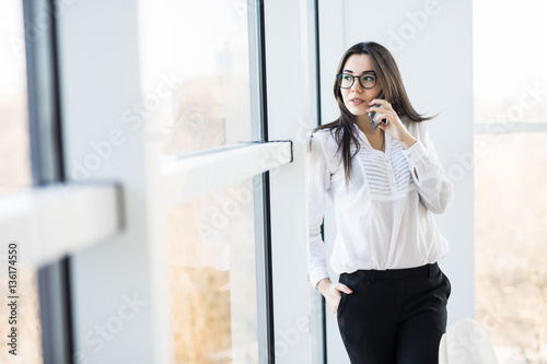 Business woman speak on phone near big office windows in modern smart space. Free Download Business woman speak on phone near big office windows in modern smart space. - GFXLoad