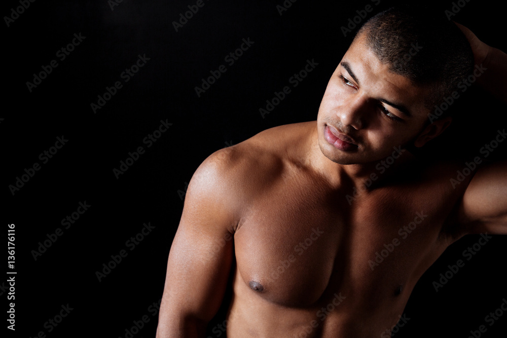Attractive naked muscular african young man standing and looking away