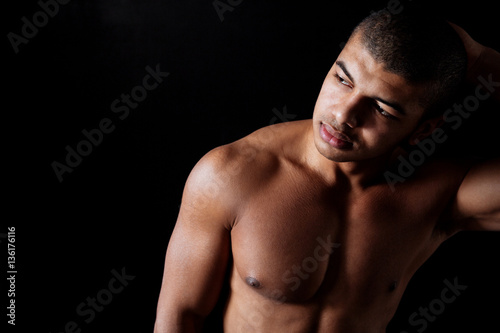 Attractive naked muscular african young man standing and looking away