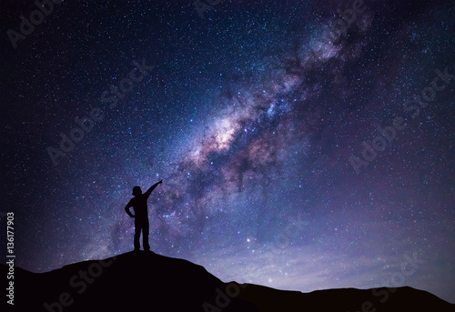 Milky Way landscape. Silhouette of Happy woman pointing to the bright star. photo