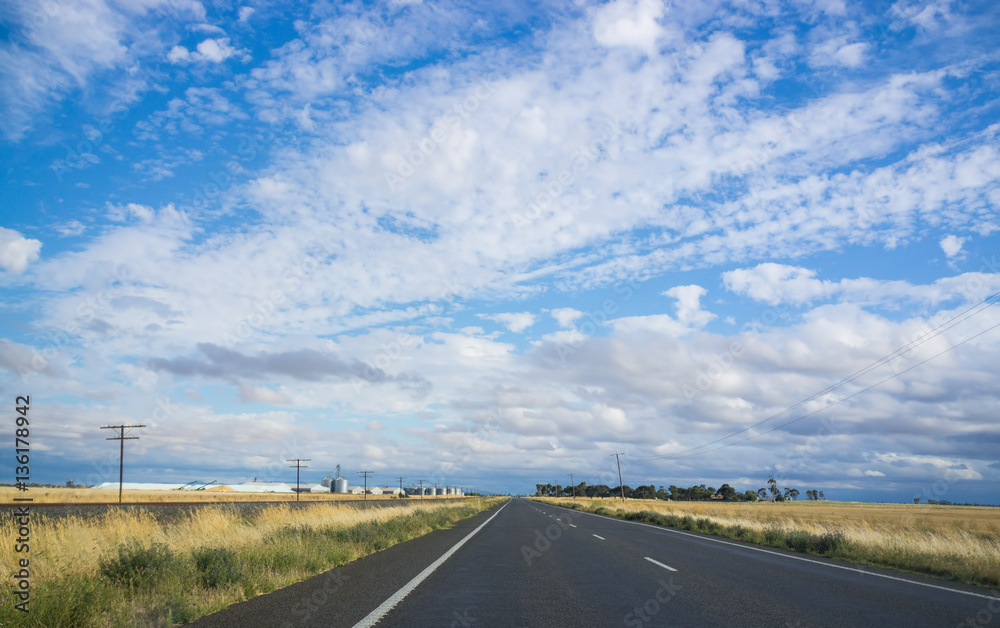 Highway among yellow fields next to railway track. Rural landscape Highway among yellow fields next to railway track. Rural landscape