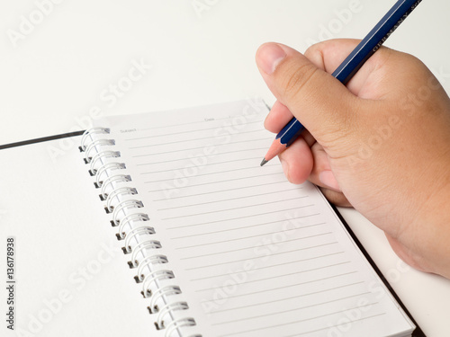 Hand writing in open notebook on table..
