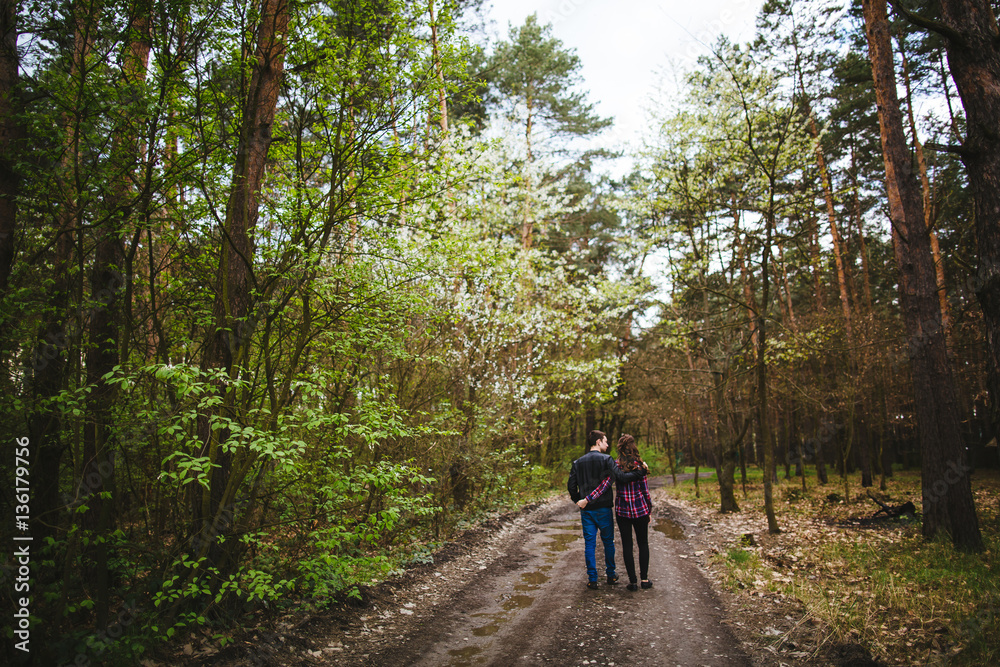 Happy young couple walking through the  forest