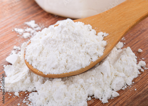 Pile of white wheat flour in wooden spoon