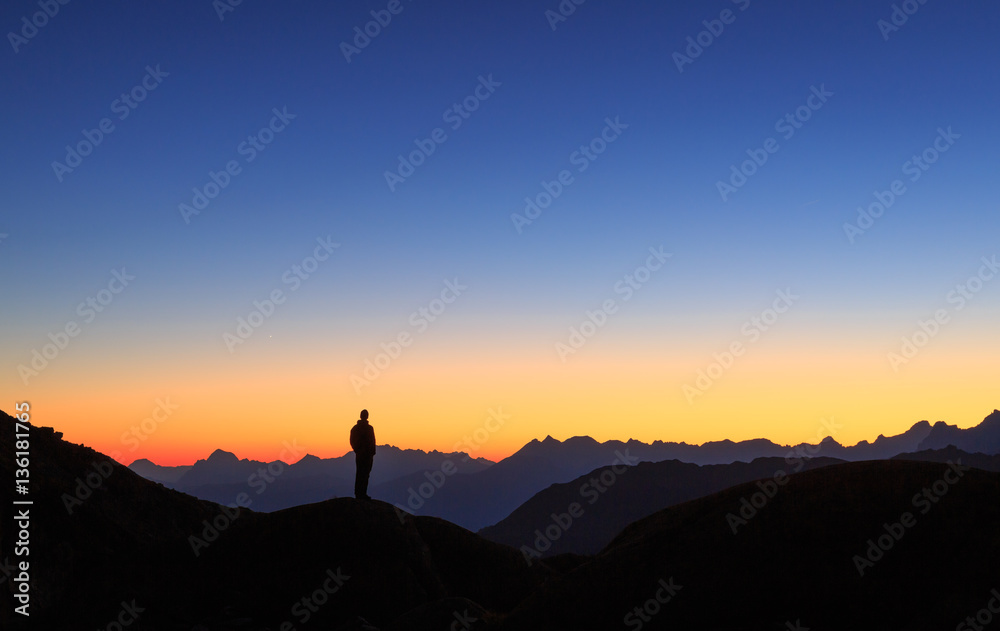 Man looking at the colorful sky in the mountains during a tranquil dusk. Man looking at the colorful sky in the mountains during a tranquil dusk.