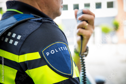 Dutch policeman with radio focus on badge with logo