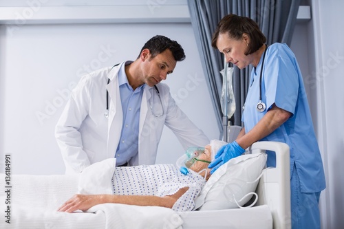 Doctors treating senior patient in ward