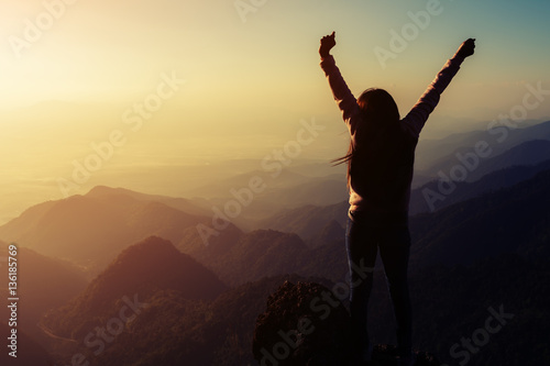 silhouette woman rising hands on mountain in morning with vintag