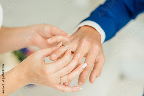 Fototapeta Naklejka Na Ścianę i Meble -  Closeup of groom placing ring on brides finger on their