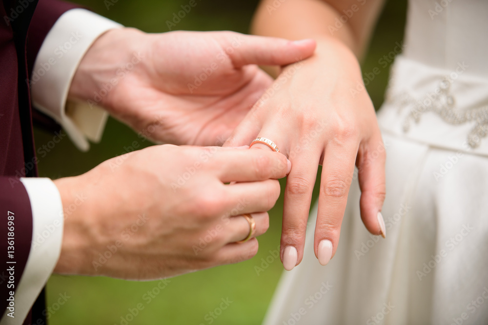 Closeup of groom placing ring on brides finger on their Closeup of groom placing ring on brides finger on their