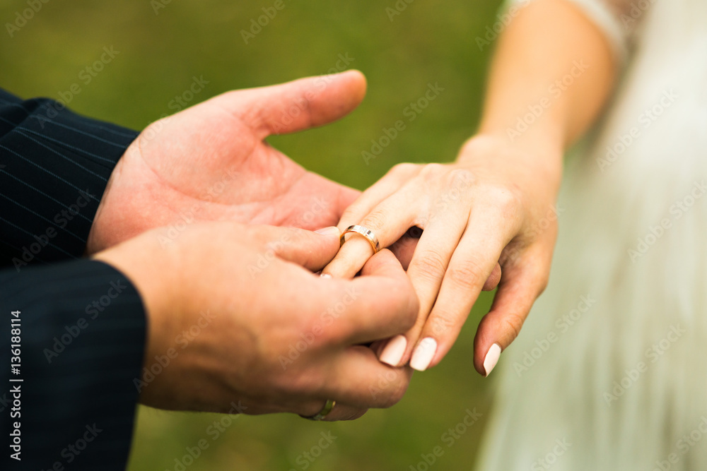 Closeup of groom placing ring on brides finger on their