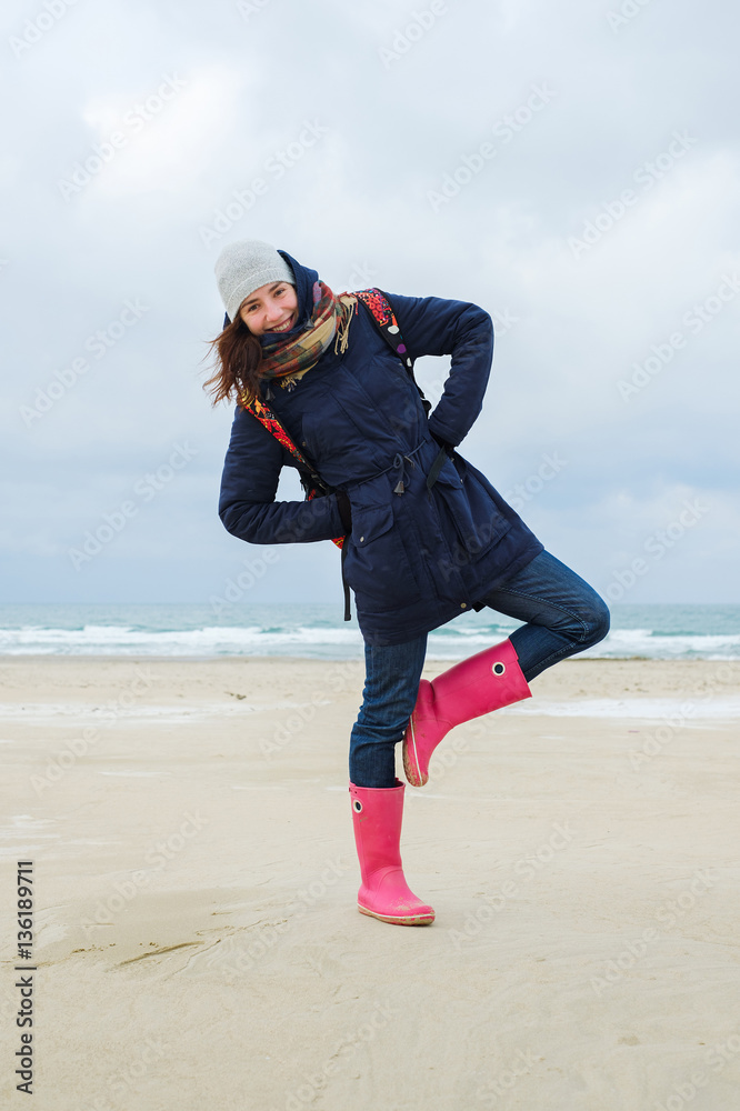 energetic funny young woman enjoying life and posing on the beach in winter.