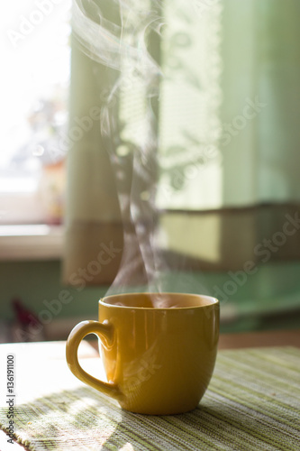 Steam of morning tea above yellow cup on table