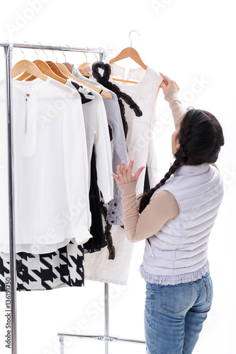 woman selects new fashion clothes on wood hangers on rack. Shopp
