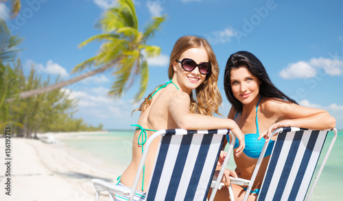 happy women sunbathing in chairs on summer beach