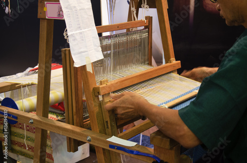 Thai people using small loom or weaving machine for weaving show
