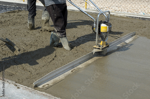 Smoothing fresh concrete with gas powered vibrating screed machine
