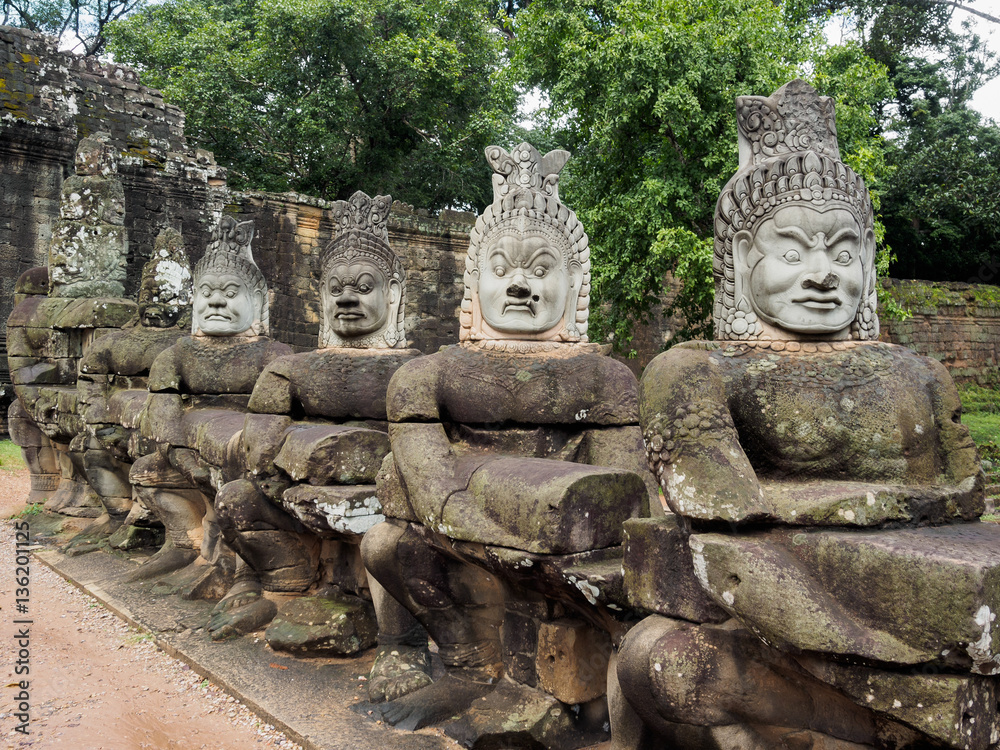 Statues of stone asura or demons with newly moulded heads at Angkor Thom, ancient capital of Khmer empire.