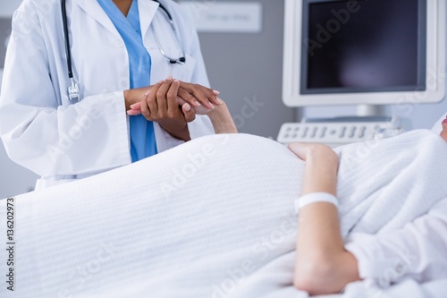 Mid section of doctor comforting pregnant woman