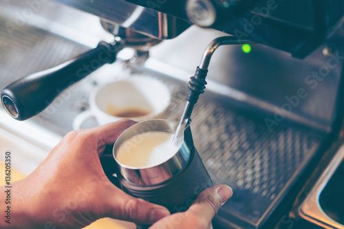 Barista using coffee machine preparing fresh coffee or latte art