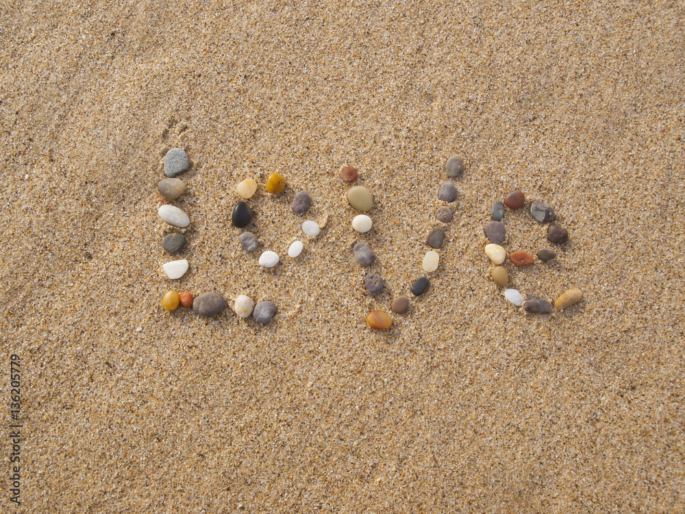 word love written with stones and shells on the beach by the ocean word love written with stones and shells on the beach by the ocean