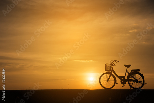 Silhouette of vintage bike .The background image is a sunset in Thailand.