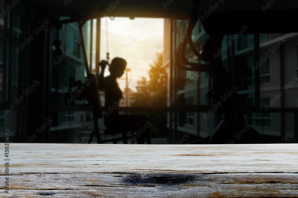 Empty top wood table and blur young fitness woman execute exerci Empty top wood table and blur young fitness woman execute exerci
