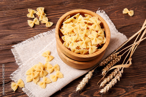 Raw pasta fettuccine in a wooden bowl